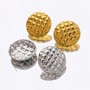 Macro detail of gold and silver ball stud earrings with classic quilted pattern texture