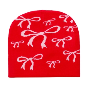 Detailed close-up of red knit beanie featuring pink bow patterns and fine stitching