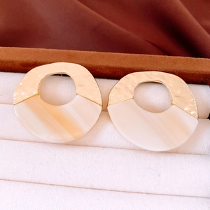 Detailed shot of gold hammered metal and cream acrylic round hollow drop earrings