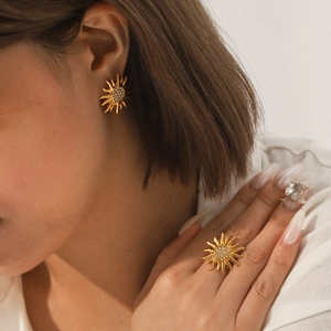 Detail of golden sunflower ring and stud earrings set with sparkling rhinestones on model