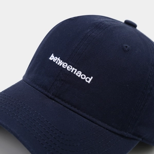 Close-up of betweenaod white letter embroidery on navy blue cotton twill baseball cap