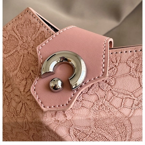 Detailed close-up of pink leather handbag texture with elegant silver arched metal buckle