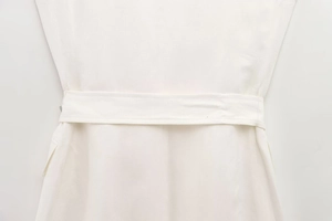 Detailed view of white cotton blend fabric with matching belt and precise stitching on dress