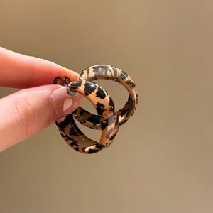 Detailed view of leopard print resin hoop earrings with a smooth polished finish