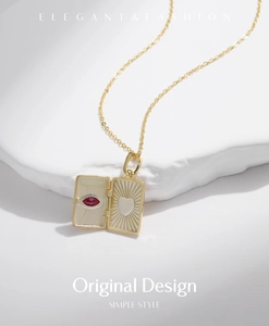 Detail of 18K gold envelope locket necklace with red marquise gemstone and heart engraving