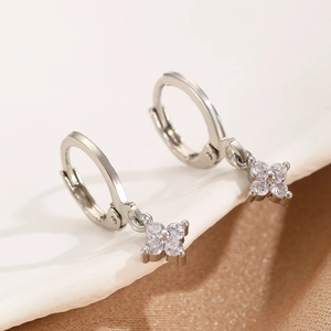 Detailed view of silver hoop earrings with clover shaped zircon pendants and crystal stones