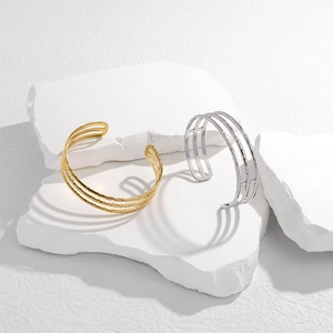 Detailed close-up of textured gold and silver triple-layered open cuff bangles on stone