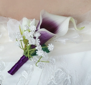 Close-up of a handmade purple calla lily boutonniere with satin ribbon and white lace