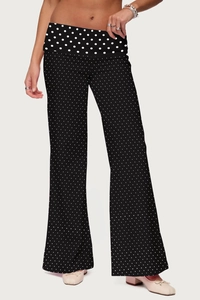 Detail of black trousers with white polka dots featuring a wide straight leg and high waist
