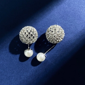 Detail of silver earring featuring a rhinestone hollow sphere and elegant white pearl