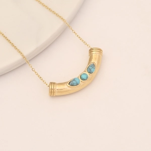 Gold evil eye necklace with curved tube pendant and turquoise stones on white stand
