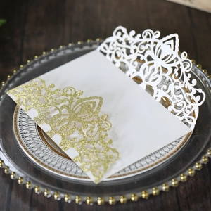 Detailed close-up of laser-cut gold glitter wedding invitation on a glass plate
