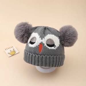 Détail du bonnet en tricot gris pour enfant avec motif hibou et deux pompons doux
