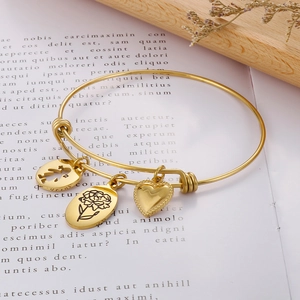 Detail of adjustable golden charm bracelet with heart and floral charms on book page