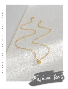 Macro detail of gold-plated dainty necklace featuring a single round zircon pendant