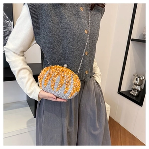 Close-up of sparkling rhinestone pumpkin clutch with silver chain and golden details