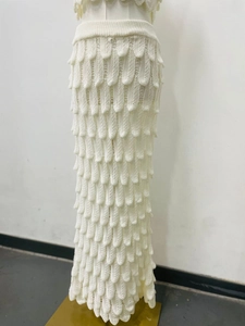 Detail view of white long skirt featuring unique tiered scale-like knit texture design
