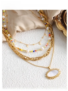 Detail of layered gold titanium necklace with pearls and white oval pendant on silk