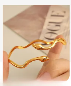 Detail of a 18K gold snake-shaped cuff bracelet featuring high-polish finish and sleek curves