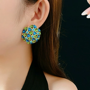 Close-up of vintage geometric earrings with blue and green gems on a gold base