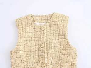 Close-up of beige tweed vest texture showing metallic gold threads and round metal buttons