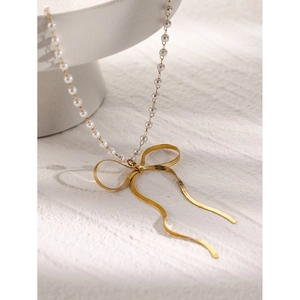 Detail of 18k gold stainless steel necklace with white pearls and a bow pendant