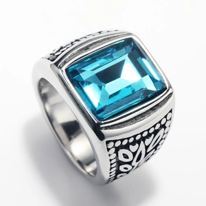 Macro detail of men's stainless steel ring featuring a blue gemstone and vintage carving