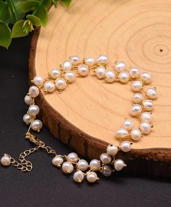 Detail of multi-layer natural pearl bracelet with golden lobster clasp on a wooden base