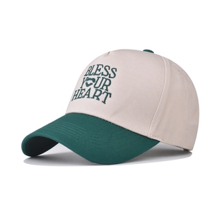 Detail of Bless Your Heart embroidery on cream and dark green cotton baseball cap
