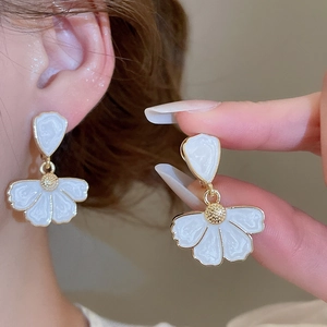 Détail de boucles d'oreilles fleurs en émail doré portées dans un style palais français