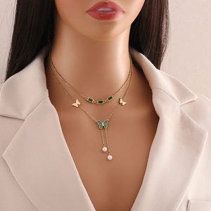 Double-layered golden necklace with emerald gemstones, gold butterflies and pearl charms