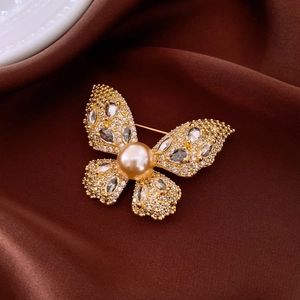 Elegant gold butterfly brooch with champagne pearl and zircon on silk background