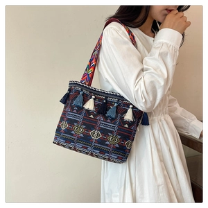 Detail of ethnic style woven tote bag with geometric patterns and colorful tassel charms