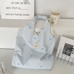 Détail du sac cabas en toile à rayures bleues avec broderies nœuds et écusson logo