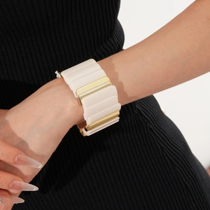 Detail of wide cream and gold geometric stretch bracelet worn on model's wrist