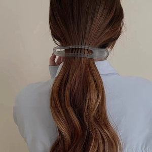 Detail of grey translucent matte shark hair clip styled on a low ponytail ponytail