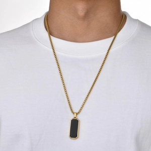 Nahaufnahme einer Goldkette mit schwarzem rechteckigem Anhänger an einem männlichen Model
