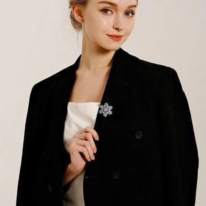 Close-up of sparkling silver snowflake brooch with diamonds on a black suit lapel