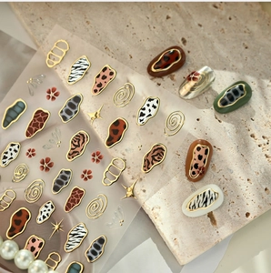 Macro detail of animal print nail stickers with metallic gold edges on beige stone