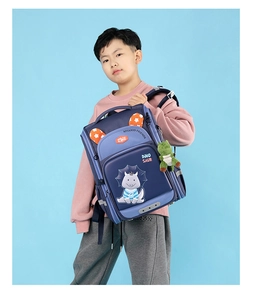 Blue children's dinosaur backpack with plush pendant shown on young boy model