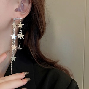 Détail de boucles d'oreilles longues à glands argentés avec étoiles et strass brillants