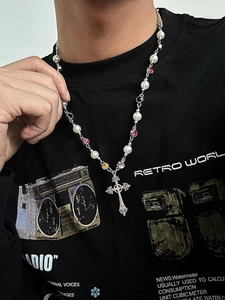 Detail of cross pendant necklace with white pearls and colorful rhinestones on a model