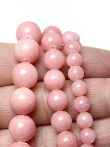 Vue macro de perles rondes roses en trois tailles pour la création de bijoux DIY