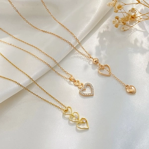 Three gold heart necklaces set with rhinestones and hollow out design on white silk