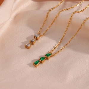 Detail of 18K gold plated necklaces with pear-cut emerald and clear crystal pendants