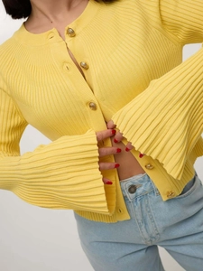 Detail of yellow knit cardigan with vintage gold buttons and flared sleeve texture