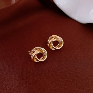 Detail shot of gold coiled hoop earrings on premium deep red velvet texture