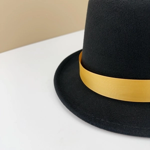 Close-up of black felt top hat featuring a shiny golden satin decorative ribbon band