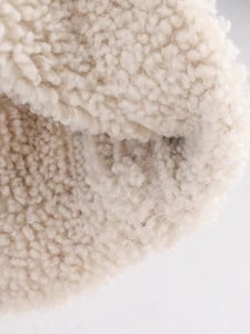 Close-up detail of soft beige sherpa fleece fabric texture on a fashion winter jacket