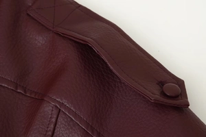 Detailed close-up of dark burgundy PU leather jacket shoulder with button and stitching